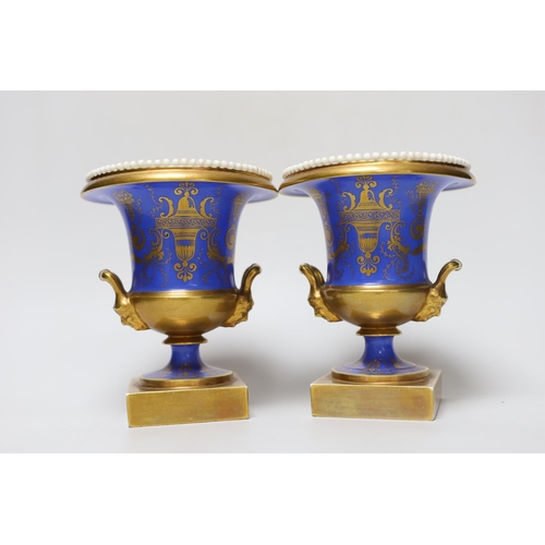 348 - A pair of Minton twin handled urn form vases, hand painted with floral motifs, in the style of Thoma... 