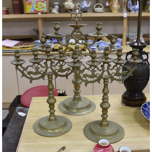 411 - Judaica - a pair of Polish brass candelabra and a similar larger candelabrum, tallest 63cm (3)... 