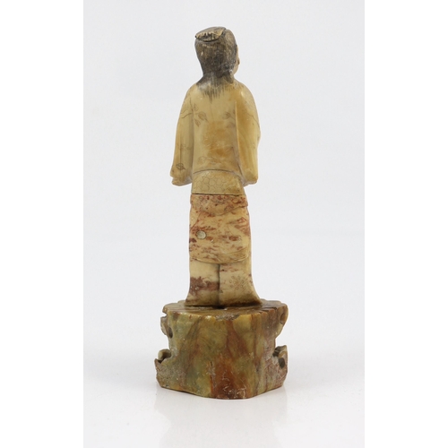 174 - A Chinese soapstone figure of an attendant, 18th century, the sectional creamy soapstone figure hold... 