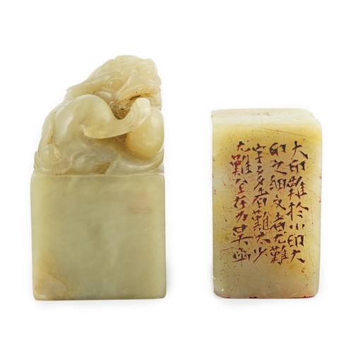 182 - Two Chinese soapstone seals, both of creamy green stone, the first surmounted by the figure of a lio... 