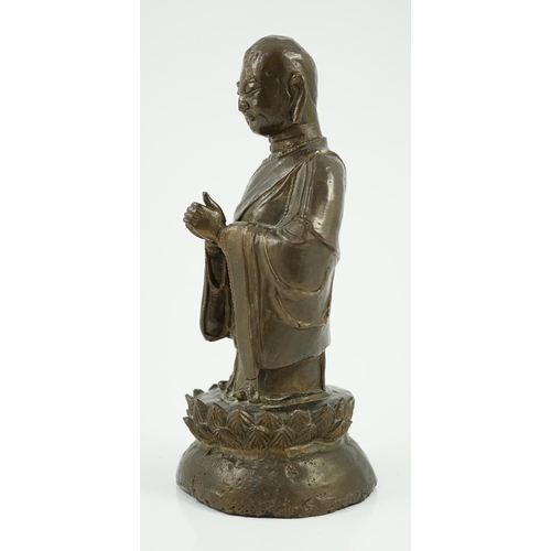 190 - A Chinese bronze figure of a standing luohan, late Ming dynasty, depicted wearing long flowing robes... 