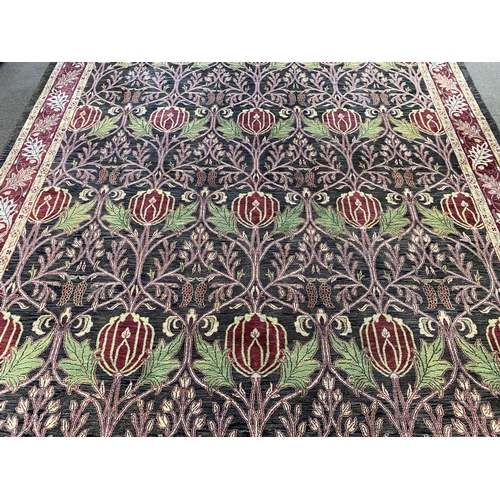 224 - A large Indian Arts & Crafts style carpet, with stylised pomegranate and flower motifs on a charcoal... 