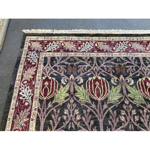 224 - A large Indian Arts & Crafts style carpet, with stylised pomegranate and flower motifs on a charcoal... 