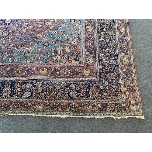 226 - A large Persian blue ground carpet, with central floral medallions radiating outwards to a palmette ... 