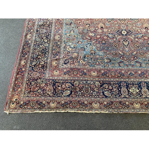 226 - A large Persian blue ground carpet, with central floral medallions radiating outwards to a palmette ... 