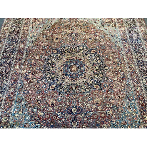 226 - A large Persian blue ground carpet, with central floral medallions radiating outwards to a palmette ... 