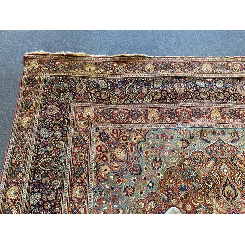 226 - A large Persian blue ground carpet, with central floral medallions radiating outwards to a palmette ... 