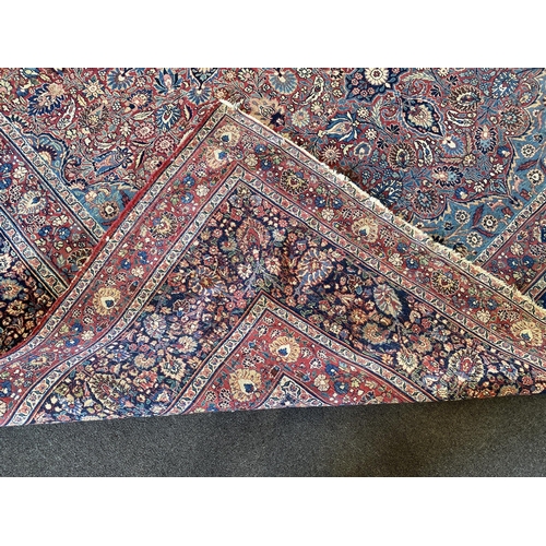 226 - A large Persian blue ground carpet, with central floral medallions radiating outwards to a palmette ... 