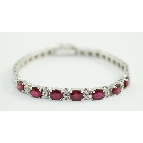 637 - A 750 white gold and seven stone oval cut ruby set line bracelet, set with sixteen stone diamond spa... 