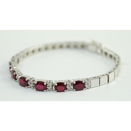 637 - A 750 white gold and seven stone oval cut ruby set line bracelet, set with sixteen stone diamond spa... 