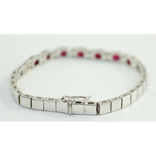 637 - A 750 white gold and seven stone oval cut ruby set line bracelet, set with sixteen stone diamond spa... 