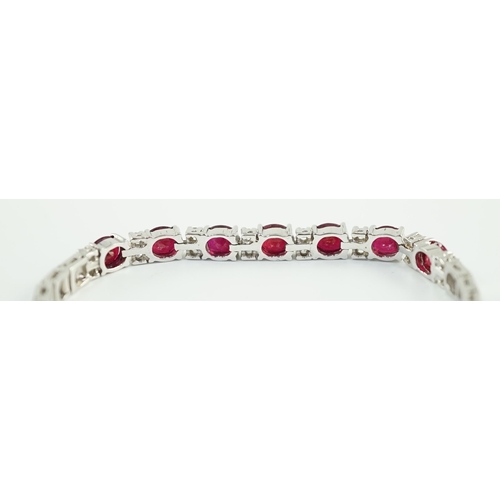 637 - A 750 white gold and seven stone oval cut ruby set line bracelet, set with sixteen stone diamond spa... 