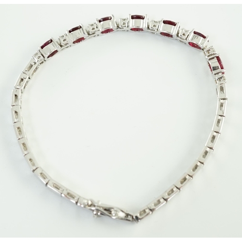 637 - A 750 white gold and seven stone oval cut ruby set line bracelet, set with sixteen stone diamond spa... 