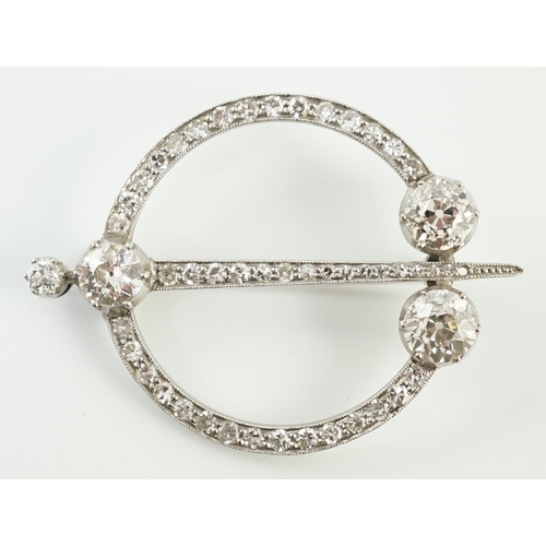 648 - A 1920's platinum or white gold, diamond cluster set openwork 'dagger and circle' brooch, set with c... 