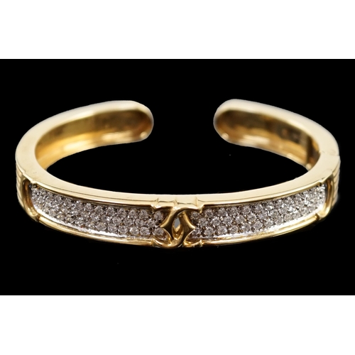 649 - A modern 18k gold and pave set diamond Cartier open work hinged bangle, with central crossed C's mot... 