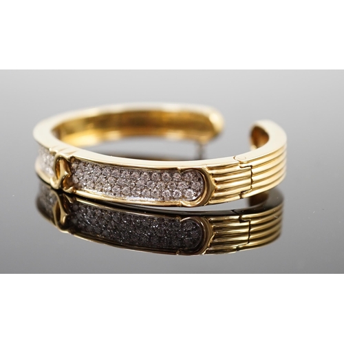 649 - A modern 18k gold and pave set diamond Cartier open work hinged bangle, with central crossed C's mot... 