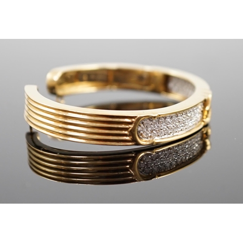 649 - A modern 18k gold and pave set diamond Cartier open work hinged bangle, with central crossed C's mot... 