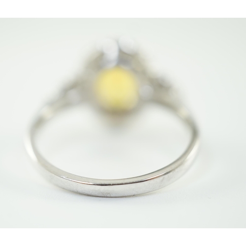 662 - A modern 18ct white gold and single oval cut yellow sapphire set ring, bordered by round cut diamond... 