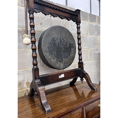 126 - An early 20th century oak dinner gong with striker, width 68cm, height 99cm