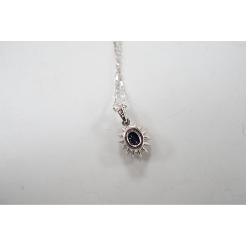 932 - A modern 9ct white gold, sapphire and diamond set oval cluster pendant, overall 15mm,on a modern 9ct... 