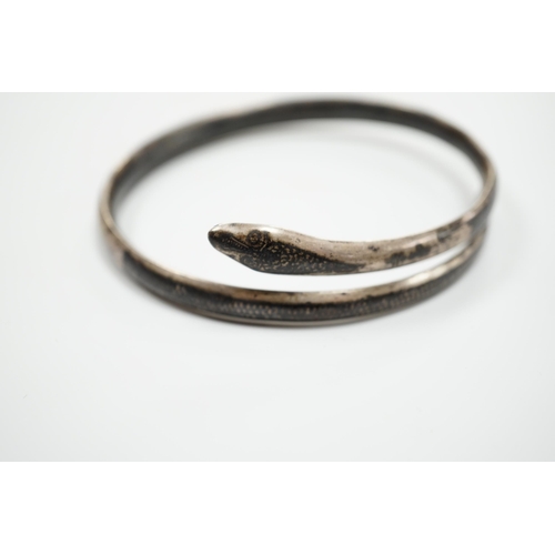 939 - A white metal and niello serpent bangle, decorated with scene of a camel train.