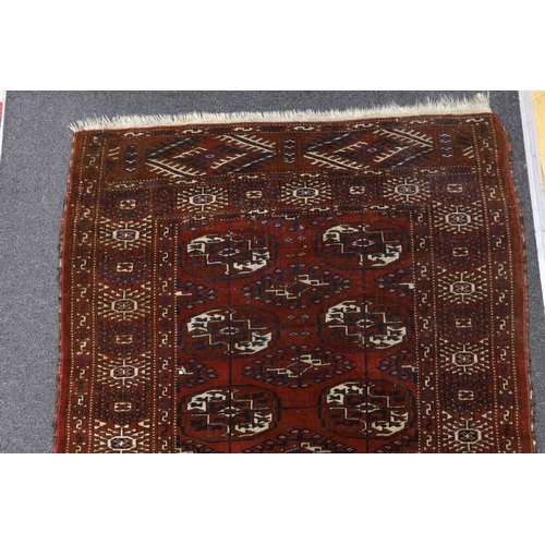 1166 - A Turkeman burgundy ground rug, 126 x 94cm