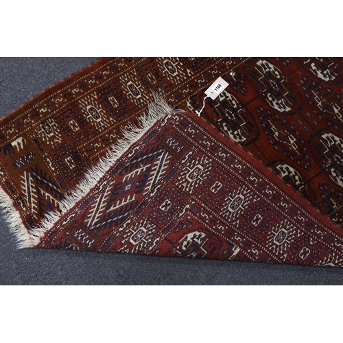 1166 - A Turkeman burgundy ground rug, 126 x 94cm