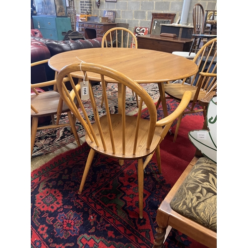 1058 - An Ercol oval elm drop leaf dining table, length 123cm extended, width 113cm, height 71cm and four E... 