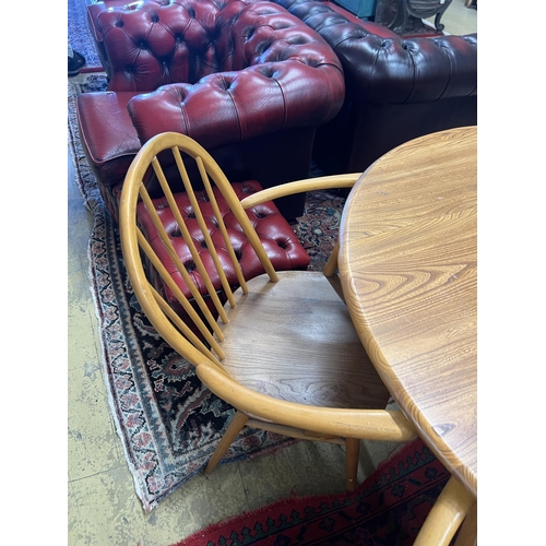 1058 - An Ercol oval elm drop leaf dining table, length 123cm extended, width 113cm, height 71cm and four E... 