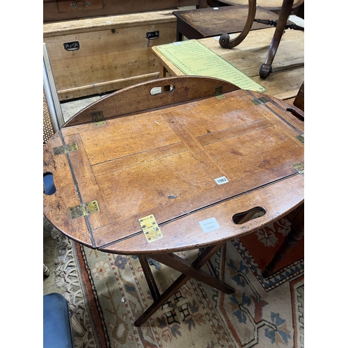 1062 - A Victorian brass mounted oval mahogany folding butler's tray / table on stand, width 90cm, height 8... 