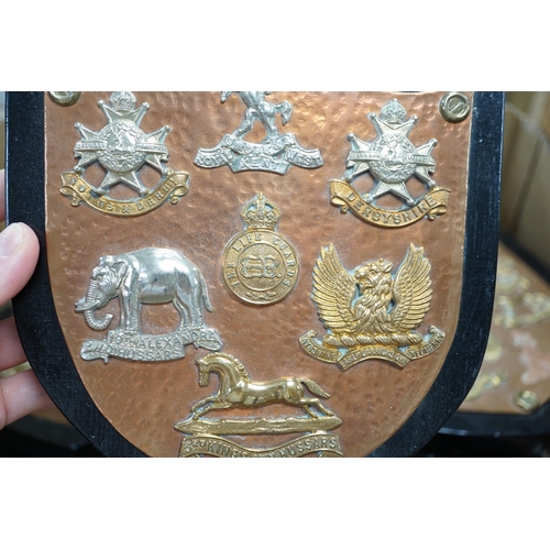 1285 - A collection of Military cap badges and buttons, with lugs removed and glued to beaten copper shield... 