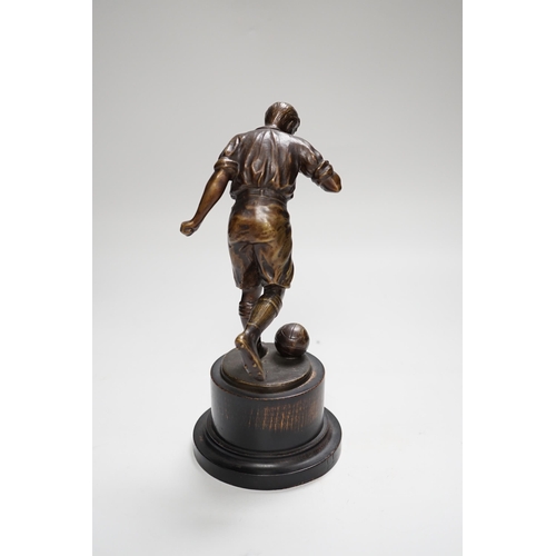 1401 - A pre-war bronze figure of a footballer, raised on a circular ebonies wood base, 23cm high