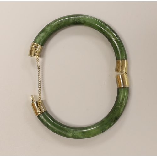 1556 - A spinach green jade bangle with metal mounts, 8.5 cm diameter (outer edge to edge)