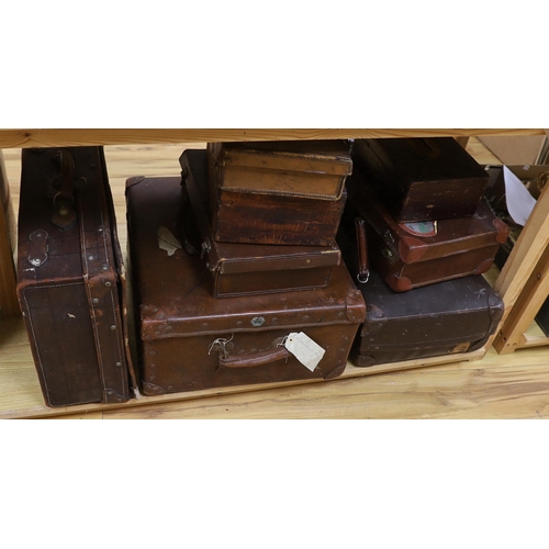 301 - Seven vintage leather suitcases and a leather writing box (locked), the largest 60cm wide