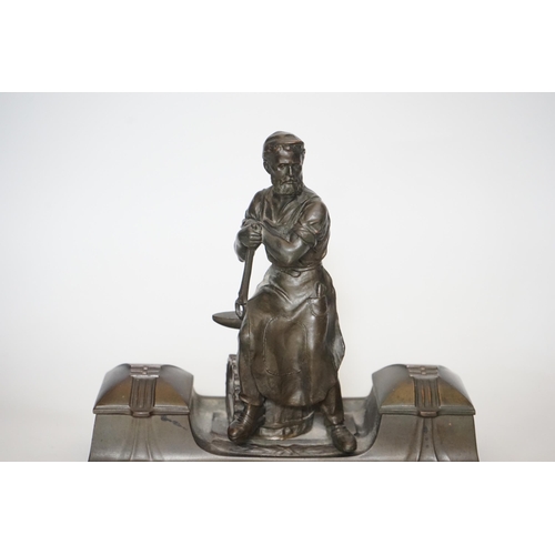 343 - A WMF style spelter Industry inkstand, figure with tools and an anvil, hinged ink wells either sid... 