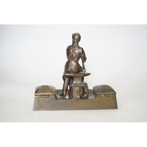 343 - A WMF style spelter Industry inkstand, figure with tools and an anvil, hinged ink wells either sid... 