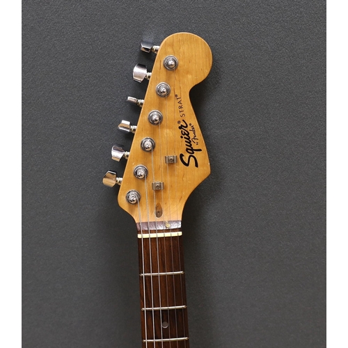 309 - A cased Squier Strat by Fender electric guitar with rosewood neck and balance lacquer body, together... 