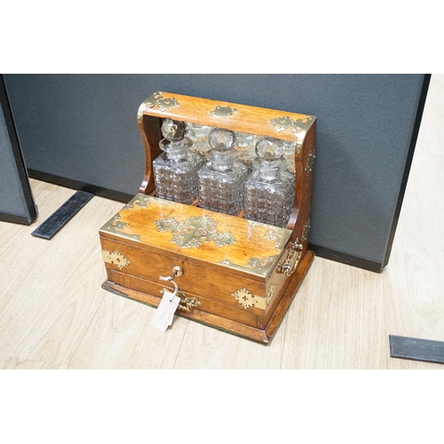 1558 - A Victorian oak and brass mounted three bottle tantalus, with base drawer and key, 36.5 cm wide... 