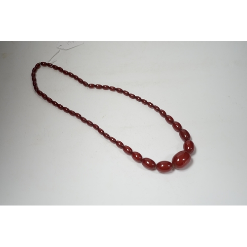 1931 - A single strand graduated oval simulated cherry amber bead necklace, 70cm, gross weight 63 grams.... 