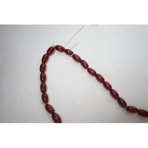 1931 - A single strand graduated oval simulated cherry amber bead necklace, 70cm, gross weight 63 grams.... 