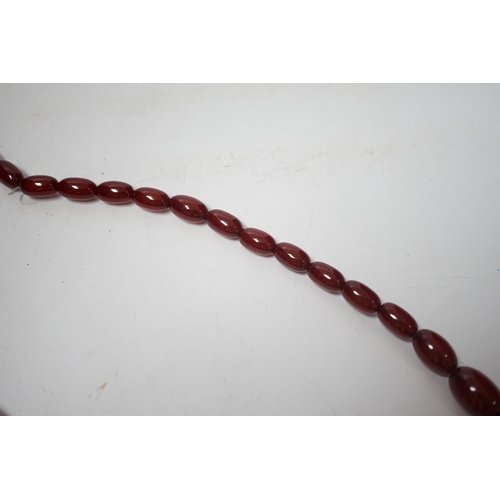 1931 - A single strand graduated oval simulated cherry amber bead necklace, 70cm, gross weight 63 grams.... 