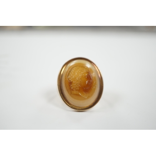 1944 - An early 20th century yellow metal and banded agate intaglio ring, carved with the head of a gentlem... 