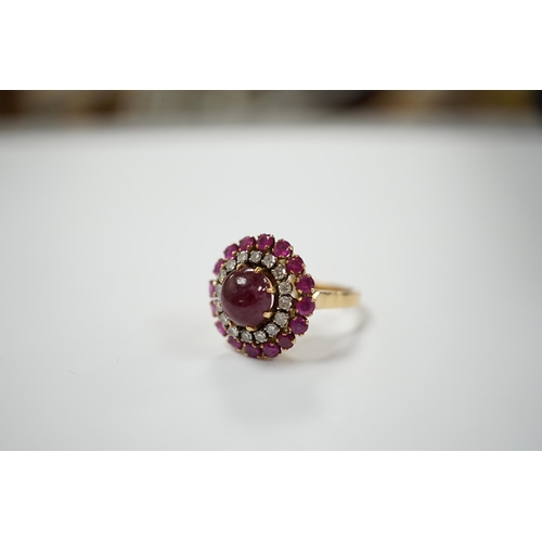 1975 - A yellow metal, ruby and diamond set circular cluster dress ring, with central cabochon ruby, size M... 