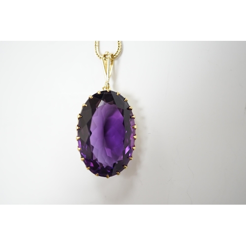 1985 - A yellow metal mounted single stone oval cut amethyst set pendant, 35mm, on a yellow metal chain, 48... 