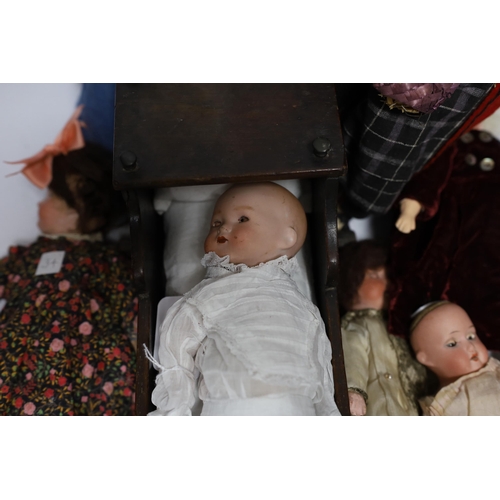 298 - Nine assorted dolls including AMS and Kewpie small doll baby in cradle