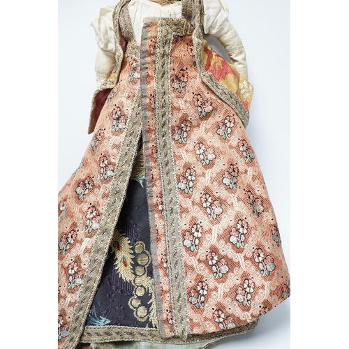 304 - An early 19th century doll with a papier mache head, glass eyes and kid leather body, dressed in 18t... 