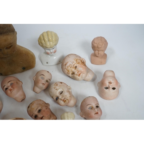 331 - Twelve small bisque doll heads and a wax head