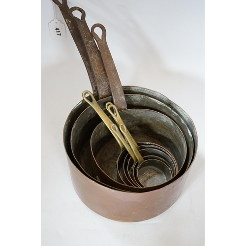 417 - A copper two handled jam pan and a graduated set of eight copper saucepans