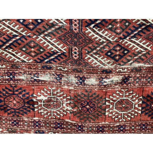 94 - ** ** A Bokhara red ground carpet, woven with rows of elephants foot, 308 x 203cm (Worn at one end) ... 