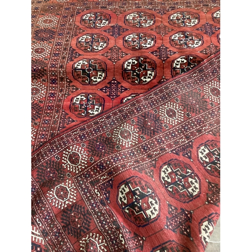 94 - ** ** A Bokhara red ground carpet, woven with rows of elephants foot, 308 x 203cm (Worn at one end) ... 